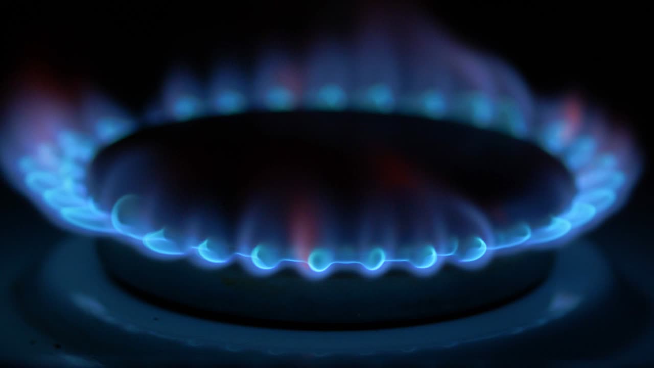 метан зажигается синим огнем на кухонной газовой плите в темной комнате. интерьер квартиры и домашнего оборудования.