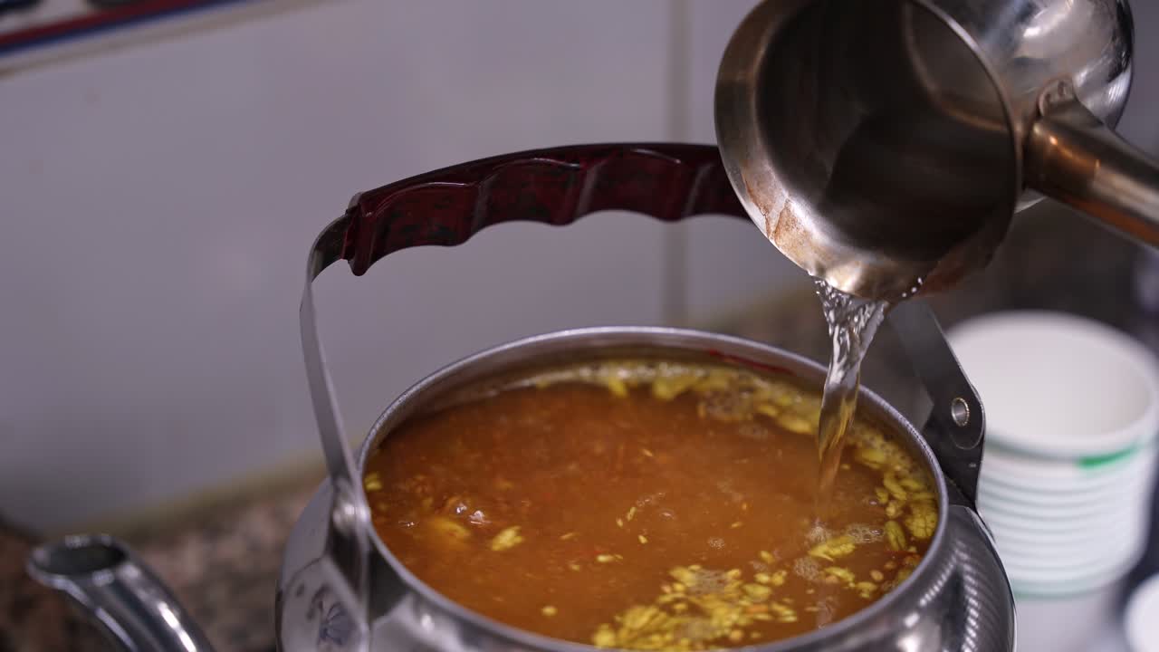 Raikasta vettä kaadetaan hopeiseen kiehuvan arabialaisen kahvin kahvipannuun. Sahramin ja mausteiden keltainen vaahto kuplii pinnalla puhtaassa keittiössä.