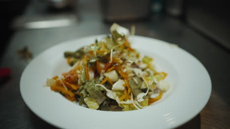 chef placing beets onto plate of salad