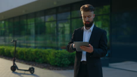 businessman using tablet outside modern building