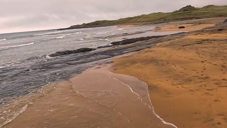 fanore beach, ireland, with dark sands and a cloudy, serene mood, aerial view