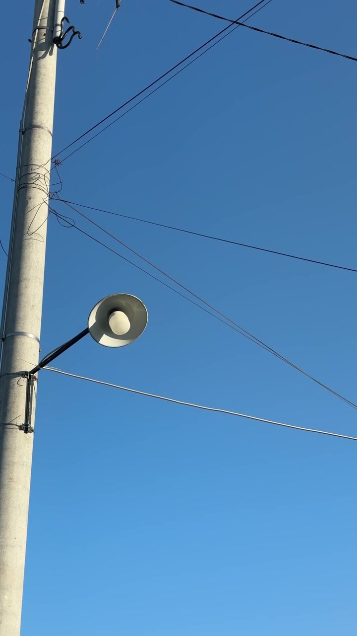 Lampu Jalan di Tiang Beton dengan Latar Langit Biru Cerah