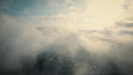 sunny morning. aerial descending among clouds over mountains