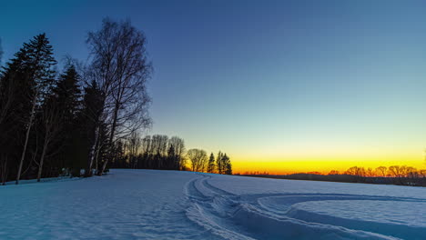 time lapse of vibrant sun setting in horizon of nordic snowfield forest, magical colors