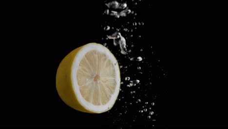 Lemon-Falling-into-Water-Super-Slowmotion,-Black-Background,-lots-of-Air-Bubbles,-4k240fps