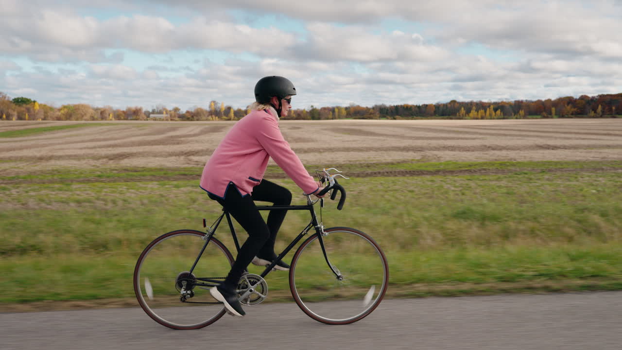 Kvinne som sykler på en vei gjennom landskapet