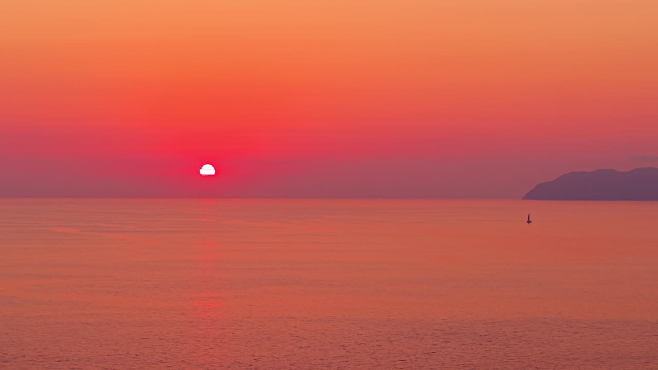 穏やかな水面と鮮やかな赤い空が広がる、静かな海の夕焼け。