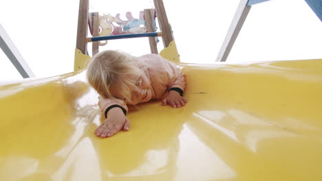 Niña-Emocionada-Divirtiéndose-En-El-Tobogán-En-El-Patio-De-Recreo