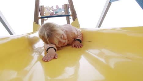 una niña emocionada divirtiéndose en el tobogán en el patio de recreo