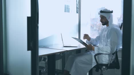 handsome man with traditional clothes working in an office of dubai