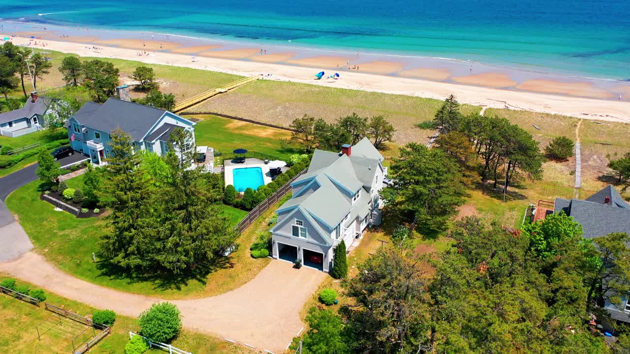 Drone footage of prime Maine beach property. Scenic house with oceanfront yard, deck, big windows, and peaceful Atlantic waves. Perfect coastal real estate for family getaways or retirement