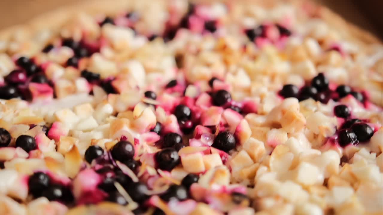 큰 둥근 달한 피자 파이와 사과 조각, 베리, 아몬드 슬라이스 및 응축 우유가 카드보드 상자에 있습니다.