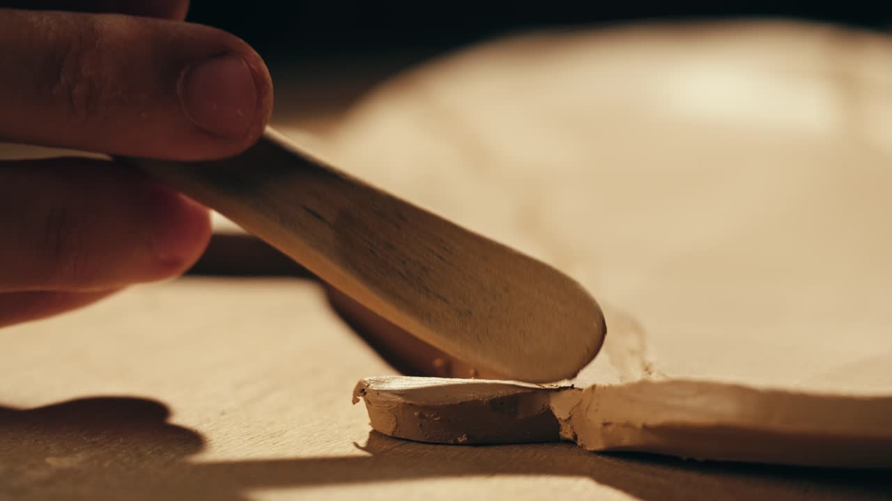 primer plano de un alfarero moldeando arcilla con una herramienta