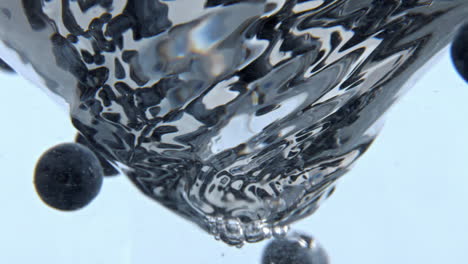 clear fruit aqua funnel inside glassware closeup. cold water spinning berries