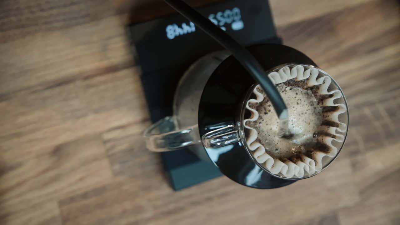 Barista making Filter coffee by spilling hot water through the filter on a scale. Slow Motion Vertical