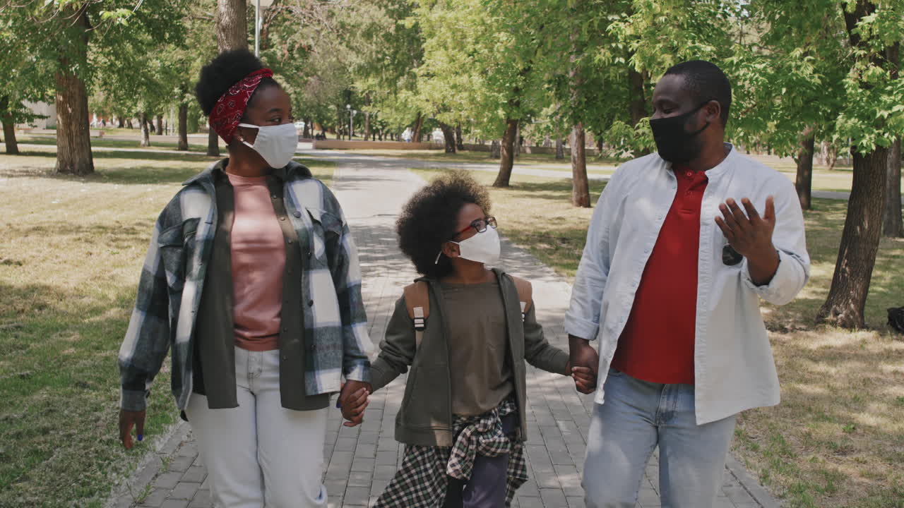 African-American Family in Face Masks Walking Outdoors