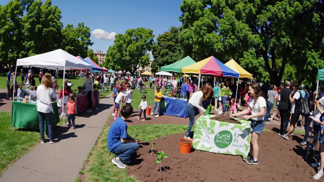 Laajakulmakuva vilkkaasta Earth Day -ulkoilmatapahtumasta, jossa on värikkäitä telttoja ja osallistujia
