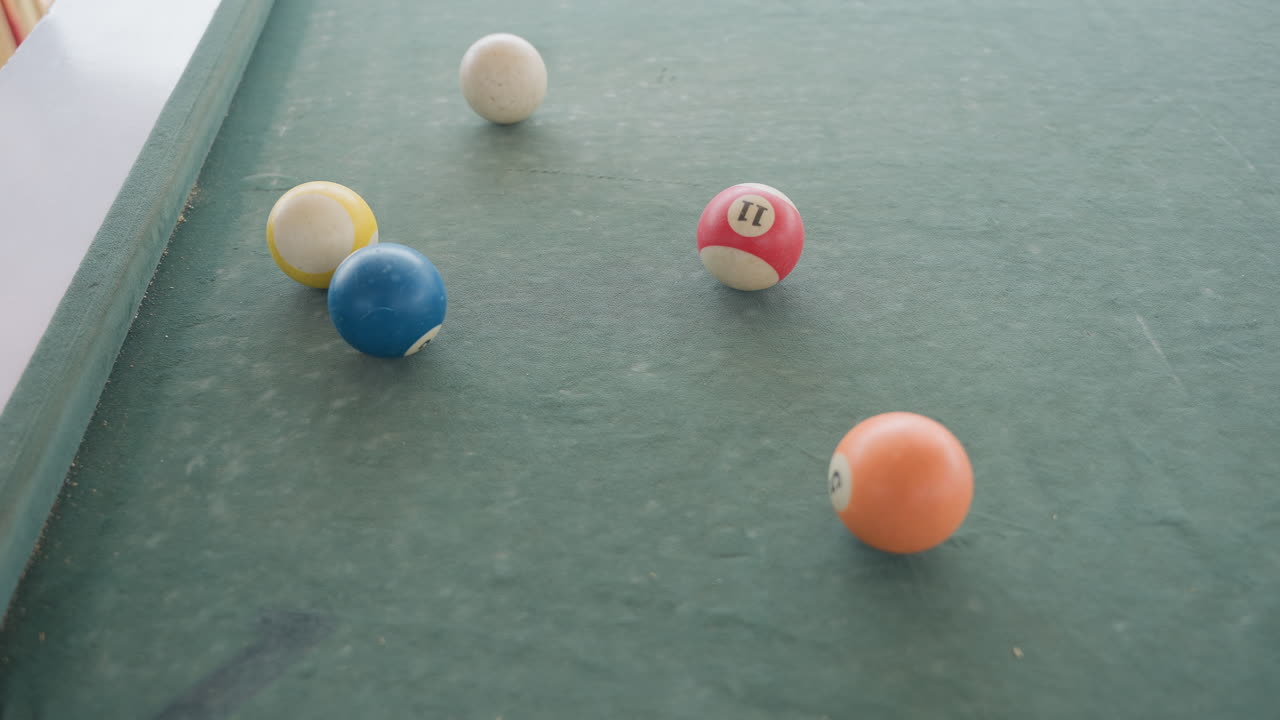 Gros plan sur des boules de billard en feutre vert roulant sur la table, une collision douce dispersant les boules colorées, de la poussière de craie subtile sur la surface texturée, lumière naturelle et faible profondeur de champ créant une atmosphère de loisirs sereine