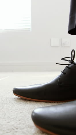 man tying a shoelaces in bedroom