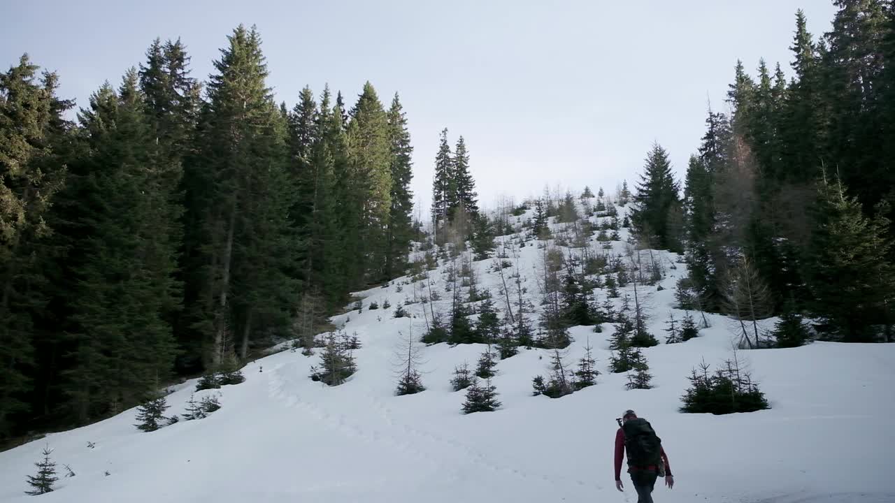 senderismo por la ladera de la montaña en nieve profunda con una mochila y cielos despejados