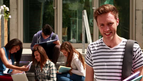 smiling student posing and friends studying behind him