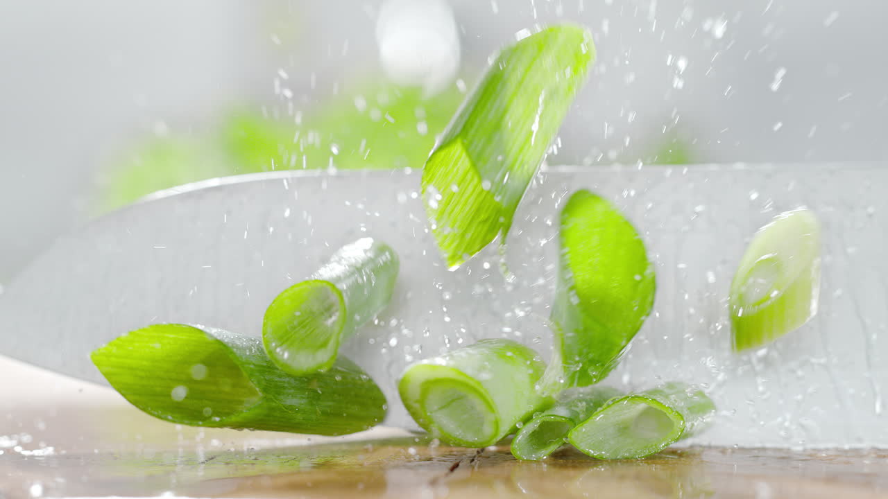 резание чеснока острым ножом на деревянной доске для резания, покрытой водой, в макро и медленном движении