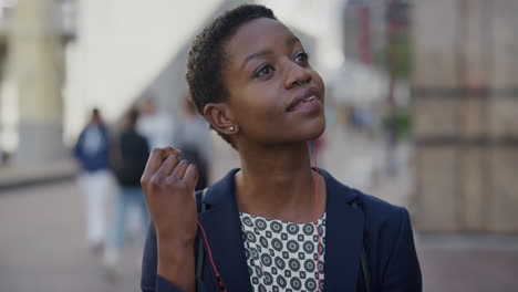 portrait beautiful young africcan american business woman listening to music takes off earphones smiling enjoying relaxed urban lifestyle in city