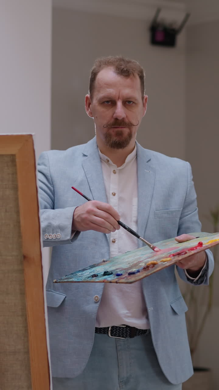 artista contempla modelo en el estudio. pintor maduro con barba estudios mujer mira para encontrar perspectiva especial en el taller. inspiración retratista