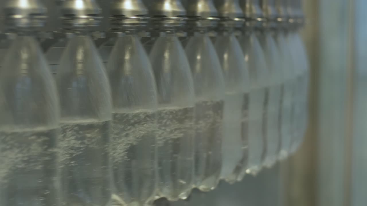 la máquina de llenado automático vierte agua en botellas de plástico para mascotas en una moderna planta de bebidas