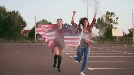 Young-Happy-American-Hipster-Girls-Running-While-Holding-The-American-Flag-And-Letting-Off-Smoke-Bomb-Grenade-With-White-Colour-Having-Fun