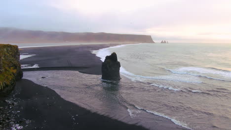 vista panorámica de las montañas, el océano y los pájaros revoloteando en un día nublado en islandia