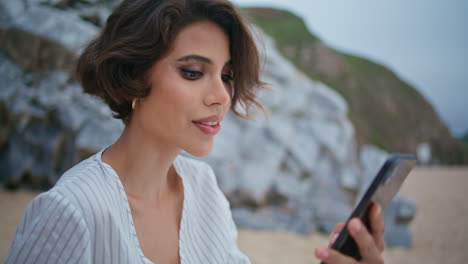 pretty lady using smartphone at seashore closeup. relaxed woman looking camera