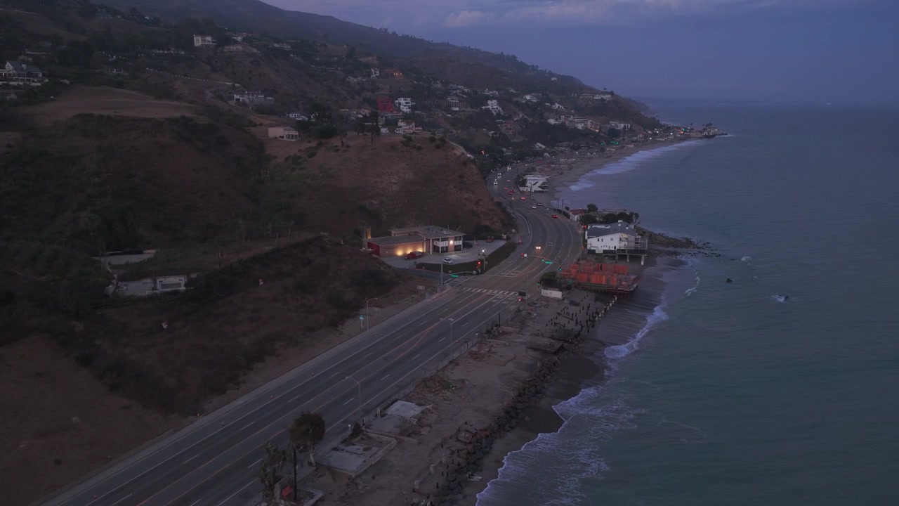 Carrellata aerea ravvicinata che vola lungo la Pacific Coast Highway vicino a Carbon Canyon al crepuscolo a Malibu, California. 4K.