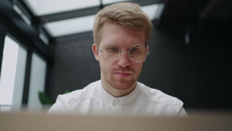 concentrated face of working man in office handsome person with glasses is looking at screen