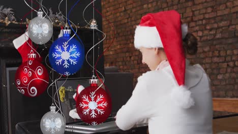 Animación-De-Decoraciones-Navideñas-Sobre-Una-Feliz-Mujer-Caucásica-Con-Sombrero-De-Santa-En-Una-Videollamada-Portátil