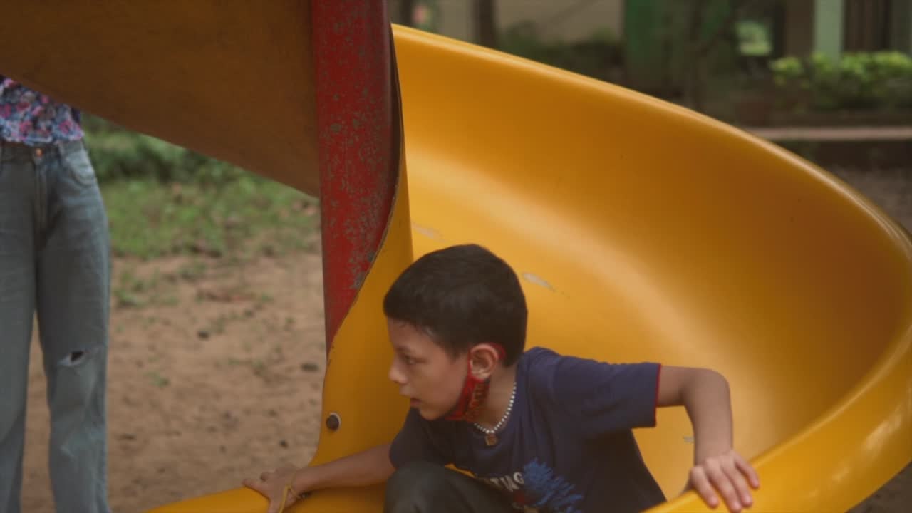niño jugando en un colorido parque infantil con un tobogán y personajes en el fondo