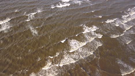 Toma-Aérea-De-Olas-Rompiendo-En-La-Playa,-Agua-De-Mar-Oscura-Y-Turbia