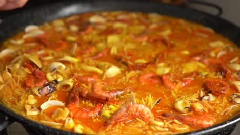 cocinar disponiendo con una cuchara el caldo de la fideuá para que quede bien repartido por el paellón