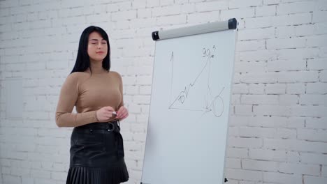 young businesswoman writing on the whiteboard. beautiful long-haired freelance girl writes with a marker on a board on the white studio background. slow motion.