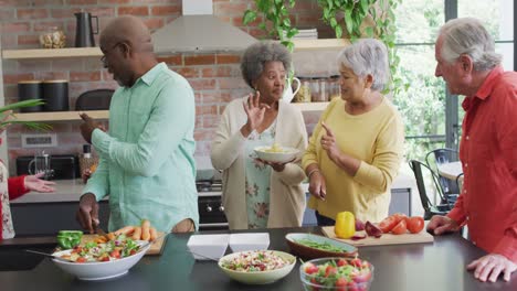 group of happy diverse senior friends cooking together in kitchen