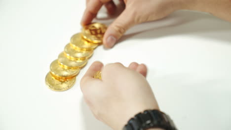 men's hands spread the gold coins bitcoin on the table. cryptocurrency in the form of gold.