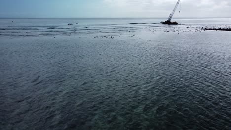 Aerial-dolly-shot-of-the-famous-shipwreck-near-nusa-lembongan-overlooking-calm-shallow-waves-in-the-sea-during-an-adventurous-and-historic-journey-through-bali,-Indonesia