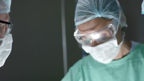 Verschiedene-Chirurgen-Mit-Gesichtsmasken-Sprechen-Während-Der-Operation-Im-Operationssaal-In-Zeitlupe