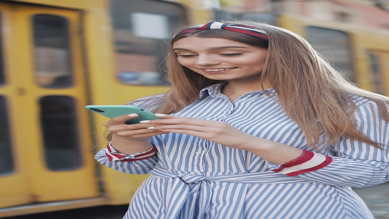 Giovane donna felice che reagisce ai contenuti sul suo smartphone in città.