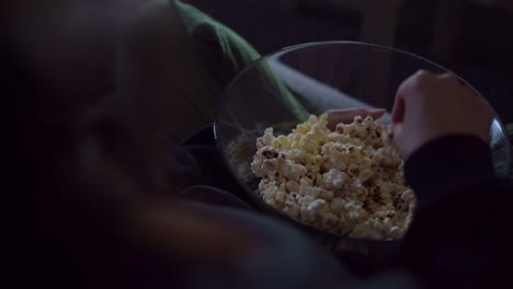 anonymous woman sitting on sofa and eating popcorn