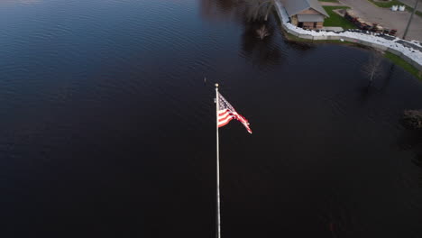 Amerikanischer-Flaggenmast-Unter-Wasser-Bei-Schweren-Überschwemmungen-Mit-Sandsackbarriere,-Die-Die-Stadt-Vor-Überschwemmungen-Schützt