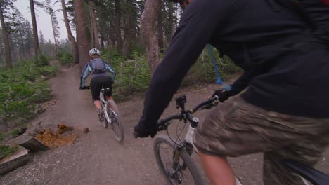 Pov-Shot-De-Ciclistas-De-Montaña-Cabalgando-Por-Un-Camino-De-Tierra-A-Través-De-Un-Bosque