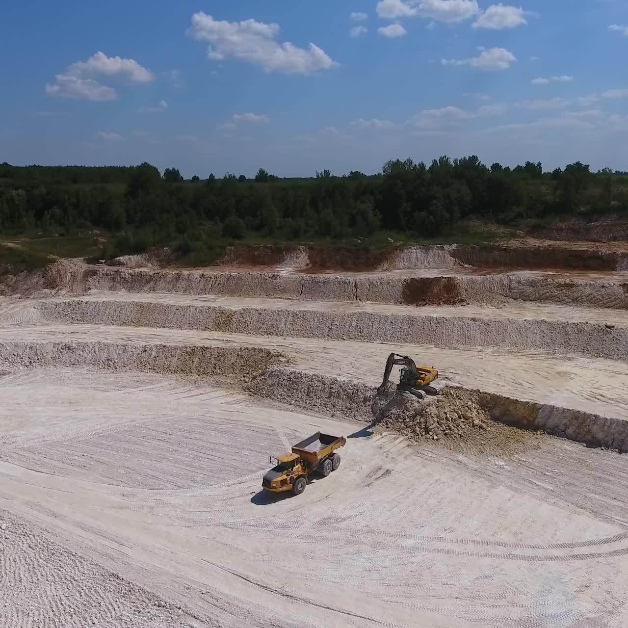 Kaolin ocağında düz zemin. Kaya oluşumlarını kazan ekskavatör makinesi. Minerallerle yüklenmek üzere yaklaşan kamyon.