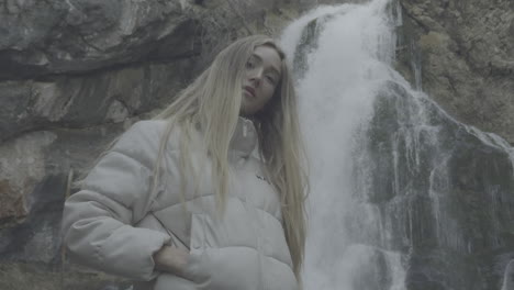 woman standing in front of a waterfall in nature