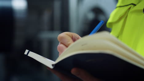 las manos de la mujer escriben datos en un cuaderno en un primer plano de una gran empresa de logística.